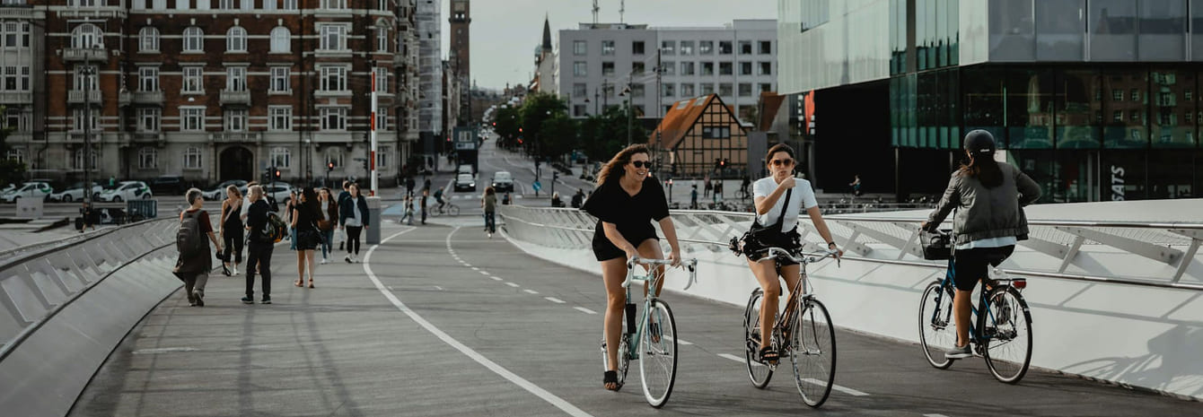Mennesker der cykler og går på en sti mellem bygninger