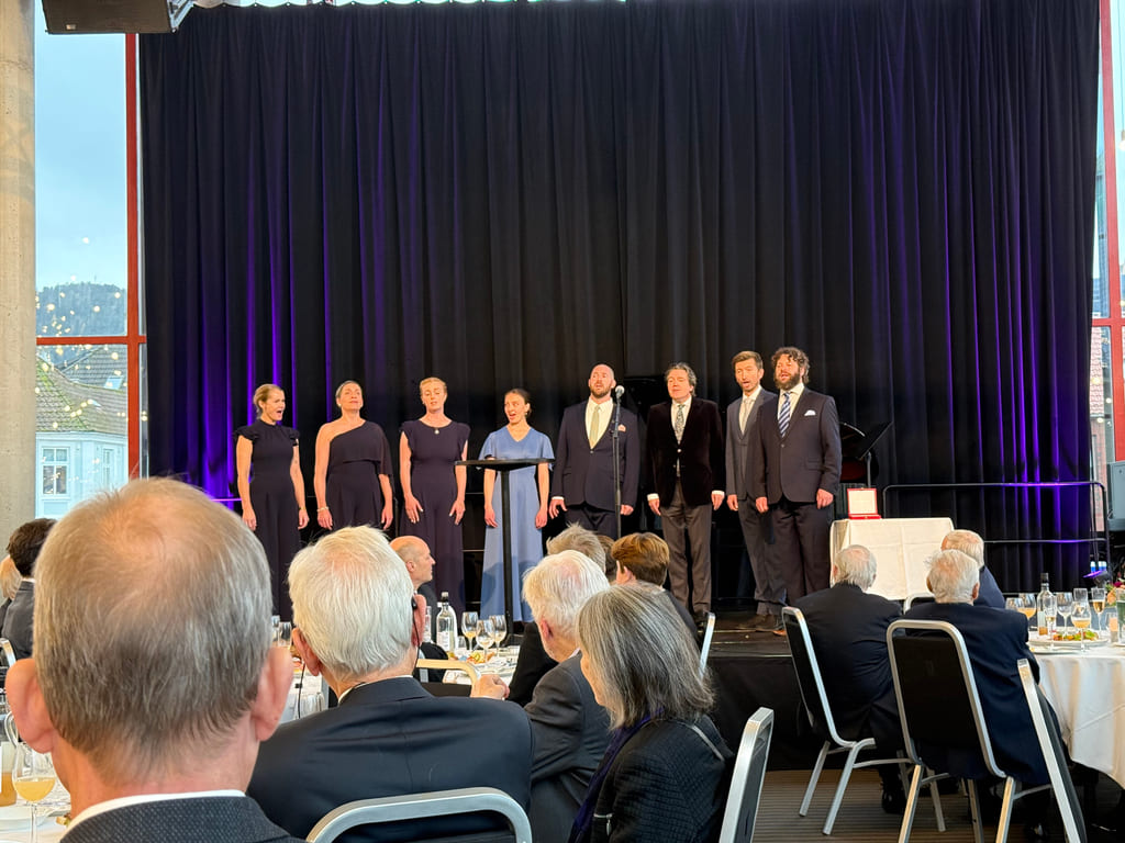 Et kor står på scenen og synger.