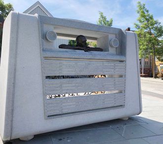 Radioskulptur: Minnesmerke etter Otto Nielsen er på plass på Bakklandstorget. Skulpturen er en to meter høy kurerradio i granitt hvor Otto Nielsen formet i bronse titter ut av ruta. (Foto: Ingunn Grøtte)