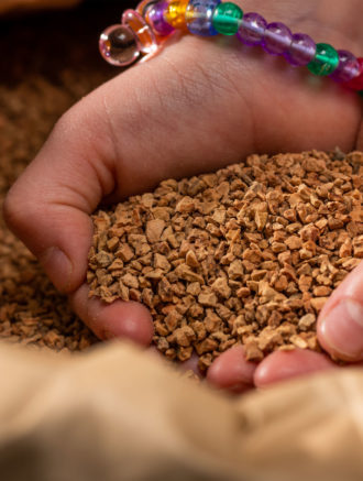 Barnehender i en pose med korkbiter