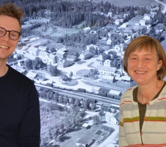 Bilde av Einar Bye og Reidunn Rustad framfor et bilde av Heimdal fra 1952.