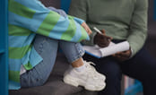 Ungdom sitter i en sofa med en voksen behandler ved siden av