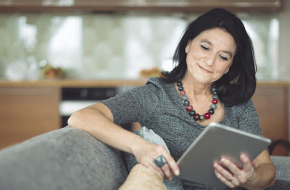 Kvinne leser på en notatbok på en sofa