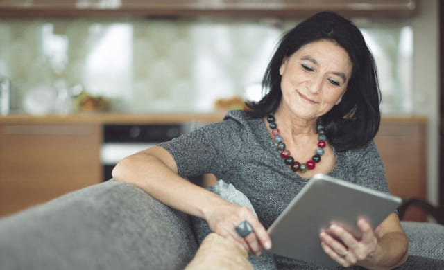 Kvinne leser på en notatbok på en sofa