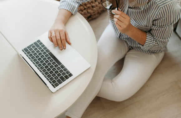 Kvinne sitter på gulvet og ser på en macbook