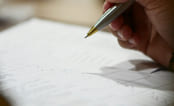 Person skriver på et ark med penn