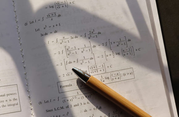 Penn og papir med matteoppgaver på