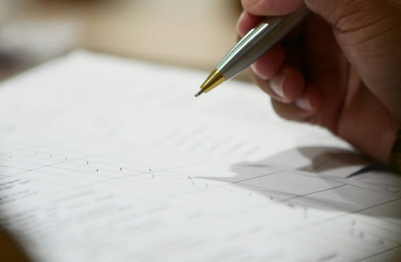 Person skriver på et ark med penn