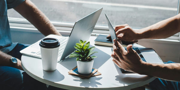 To personer sitter ved et rundt bord med to bærbare datamaskiner.